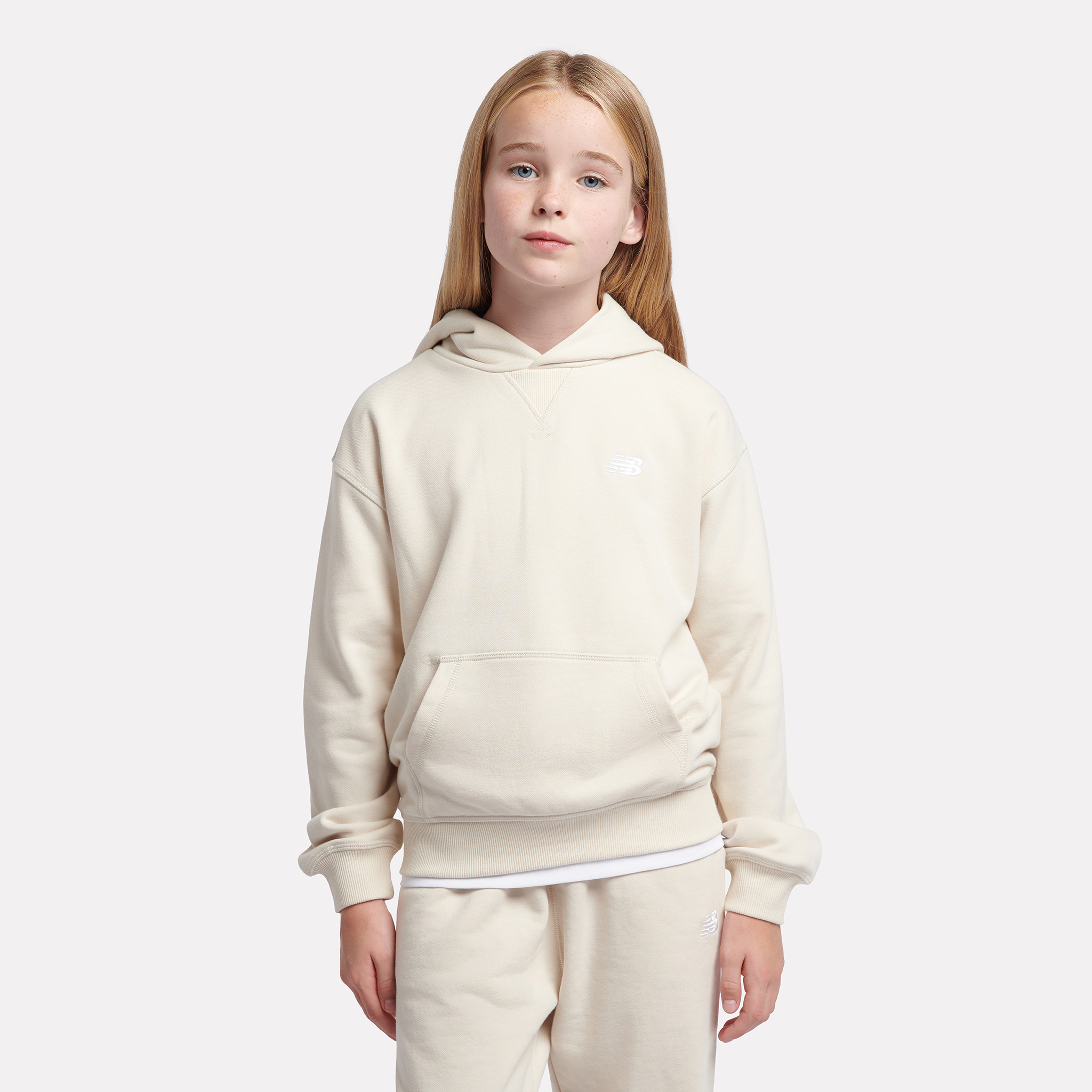 

Dětská mikina New Balance LAKG0056LIN – béžové